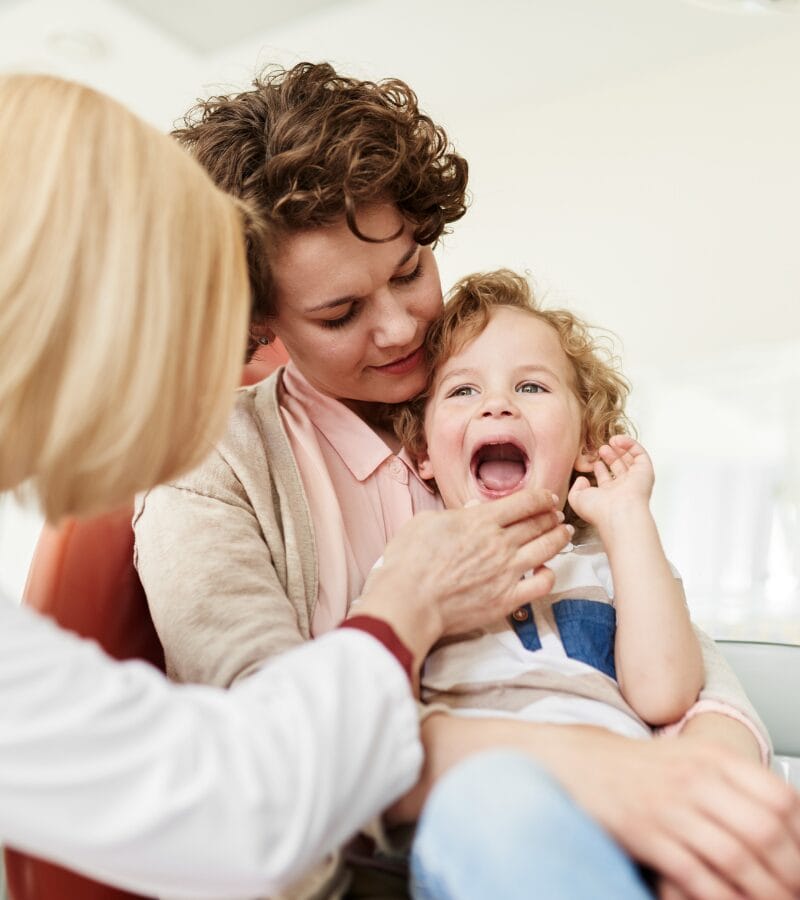 Child sitting on mother’s lap during dental exam